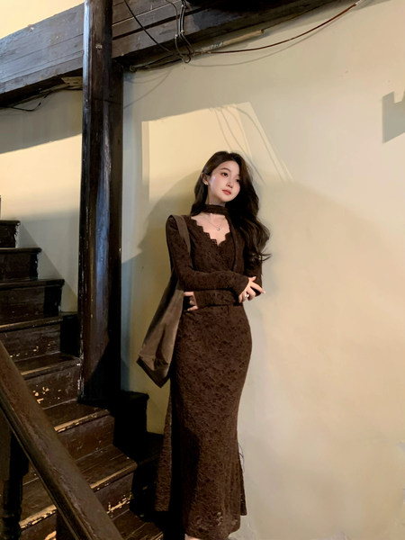 Model wearing a long brown lace dress with long sleeves and choker neckline