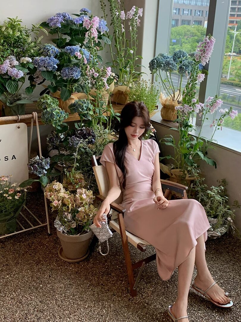 Woman wearing a light pink midi dress seated in a flower shop