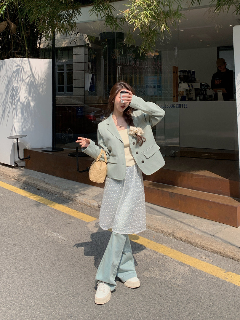 Woman wearing a pastel blazer, skirt, and flared pants outfit on a city street