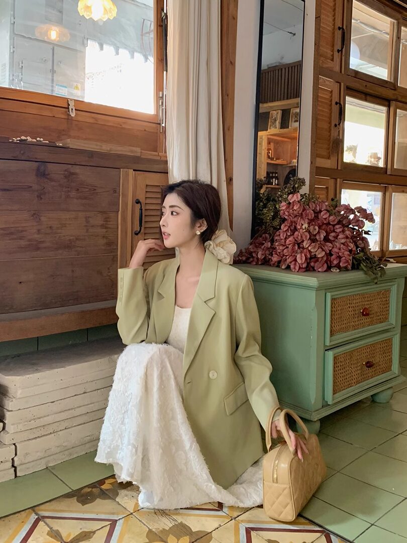 Woman wearing a light green oversized blazer with a white dress/skirt outfit