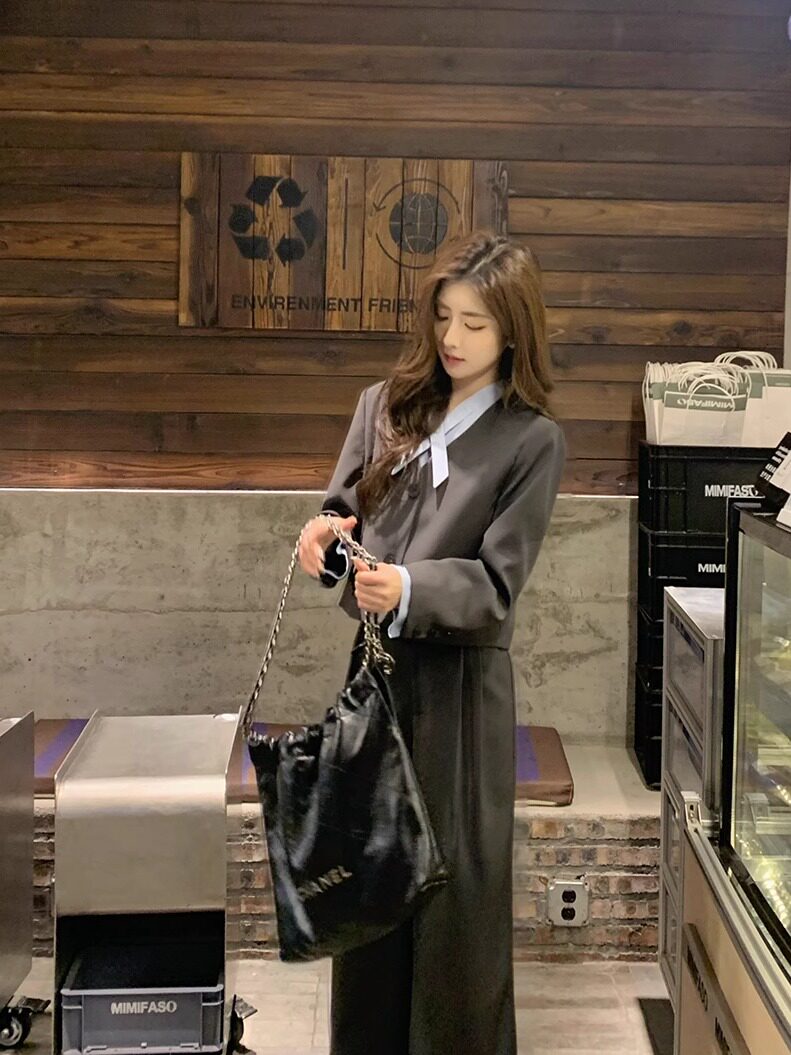 Woman wearing a gray long-sleeve dress or matching set and holding a black handbag