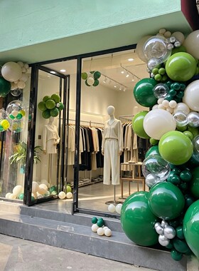 森系绿色调的店铺门头气球链布置商场服装店开业周年庆活动场景