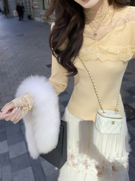 Woman wearing a cream lace-trimmed outfit with a quilted mini handbag and fluffy fur muff