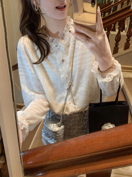 Woman wearing a white lace blouse and sequined skirt with a small silver handbag in a mirror selfie