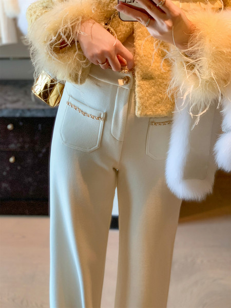 Cream tailored pants worn with a fuzzy coat and gold chain details