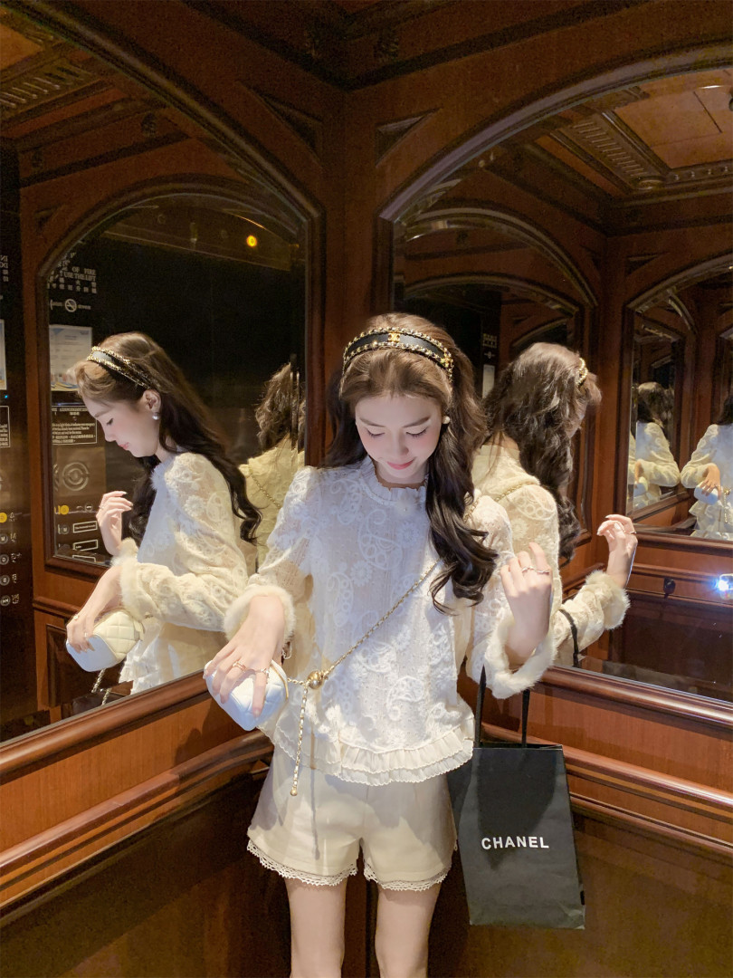 Woman wearing a white lace blouse with shorts and a headband in a mirrored elevator