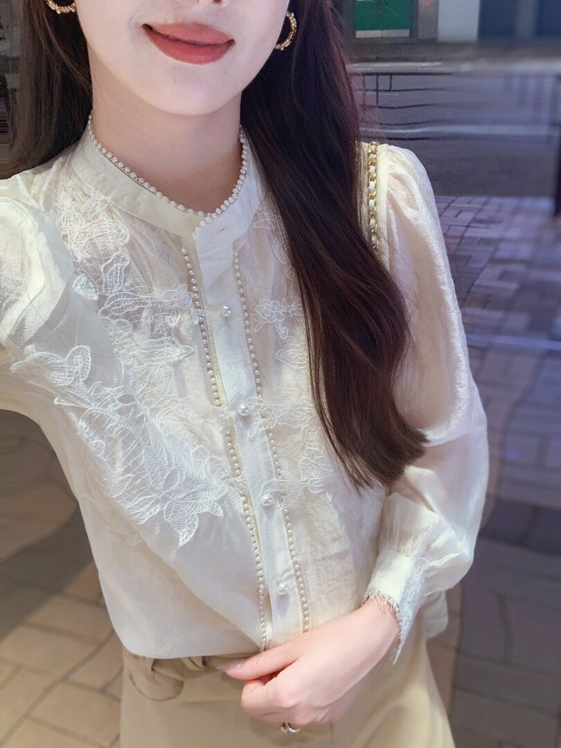 White sheer floral embroidered blouse worn by a woman