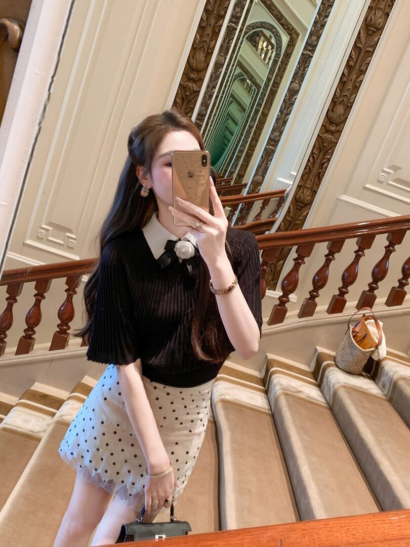 Woman wearing a black top and white polka dot skirt in a mirror selfie