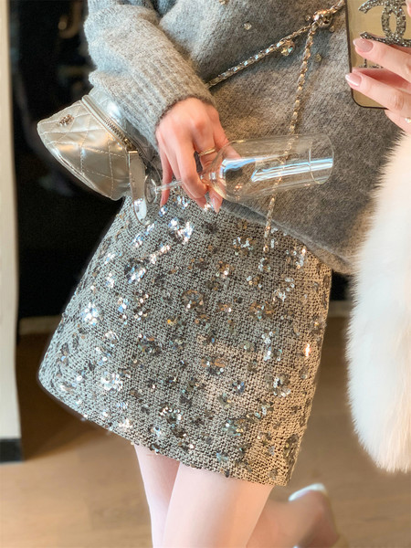 Model wearing a silver sequin skirt with a gray sweater and quilted shoulder bag