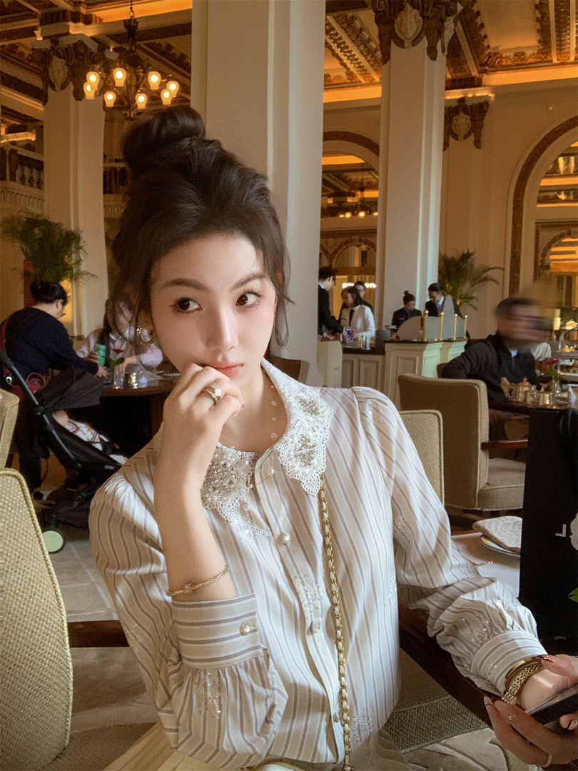 Woman wearing a striped lace-collar blouse in a restaurant