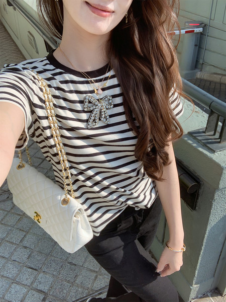 Woman wearing a black-and-white striped short-sleeve top with a white chain-strap bag