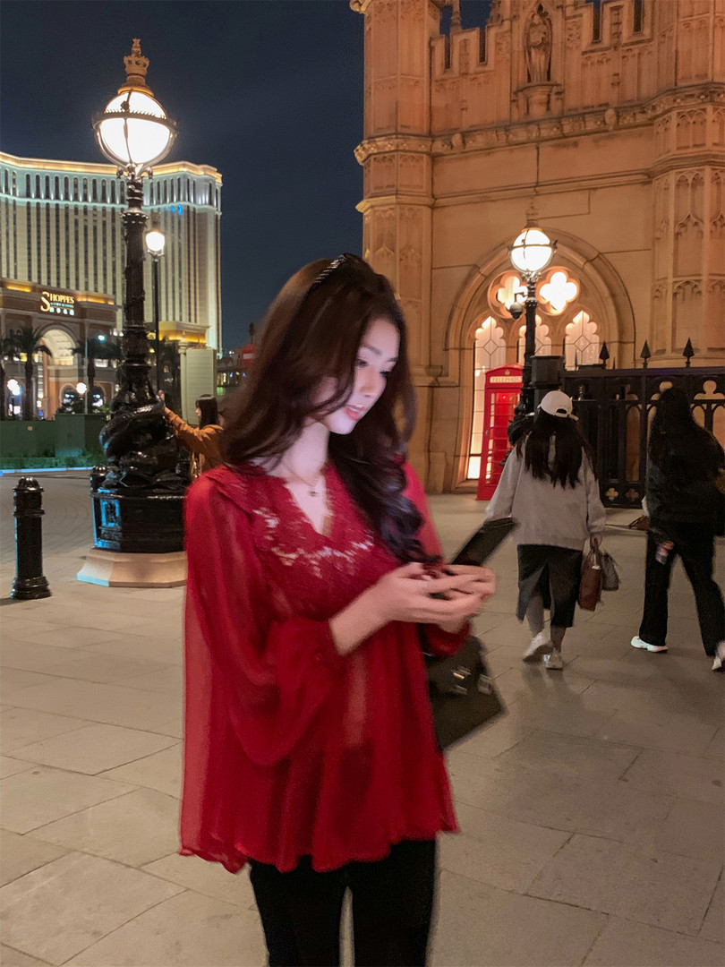 Woman wearing a red sheer lace blouse at night