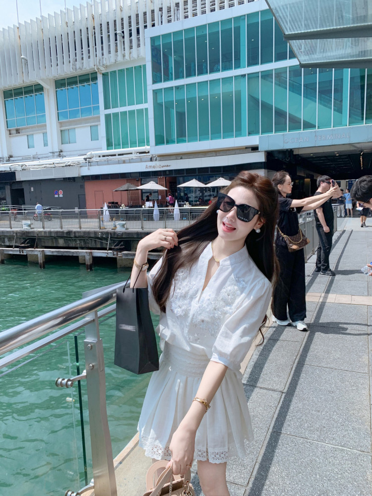 Woman wearing a white short-sleeve dress outdoors by the waterfront