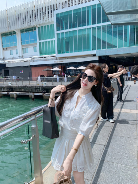Woman wearing a white short-sleeve dress outdoors by the waterfront