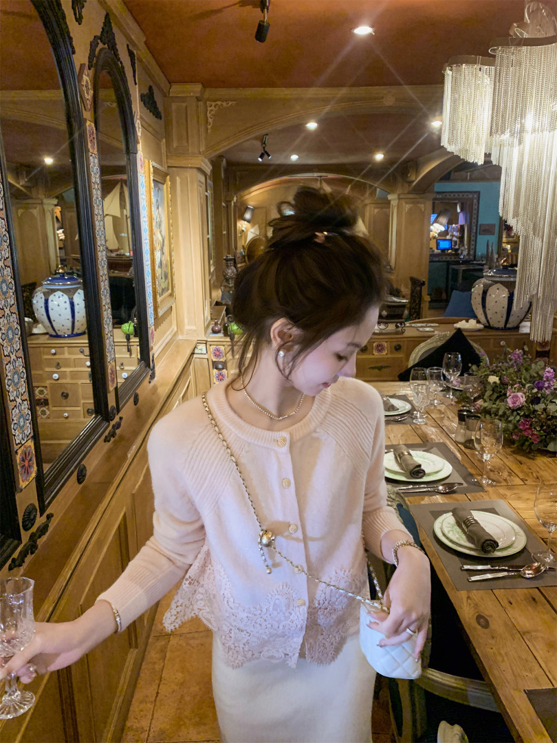 Woman wearing a light pink knit dress with lace detail in a restaurant setting