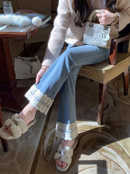 Woman wearing blue wide-leg jeans with lace hem, a fuzzy beige sweater, and fluffy slippers