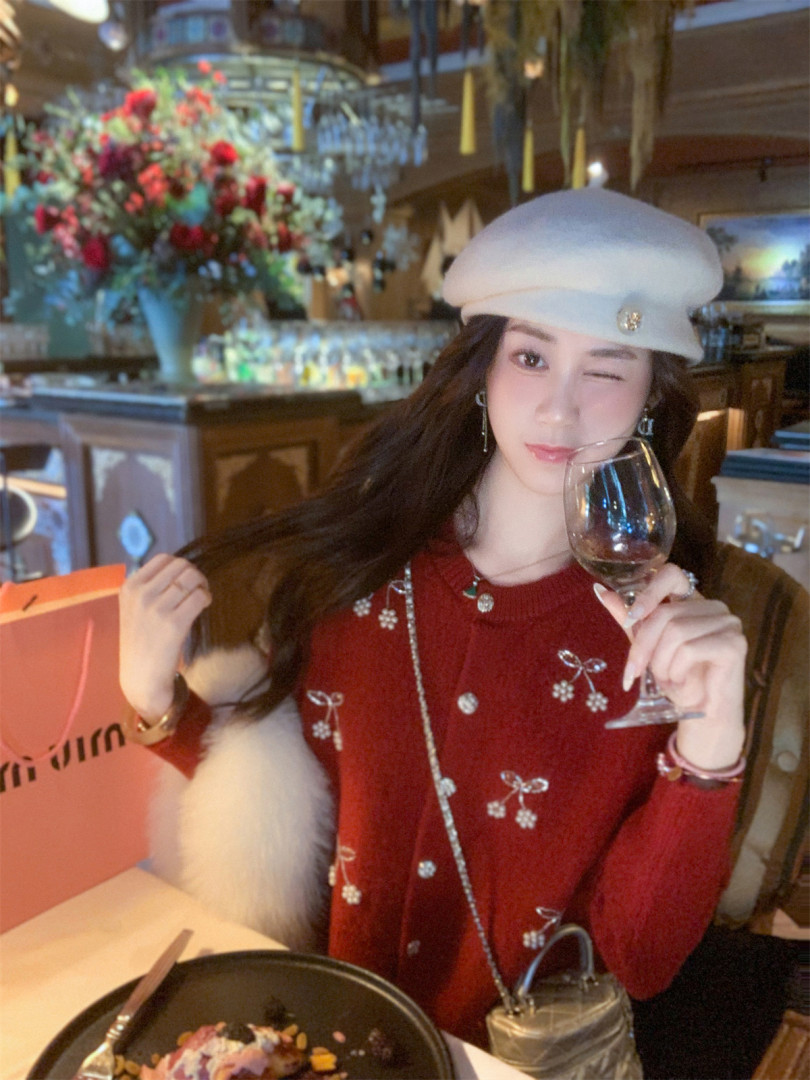 Woman wearing a red embellished sweater and white beret at a restaurant