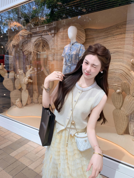 Woman wearing a light sleeveless knit top and pleated skirt outfit