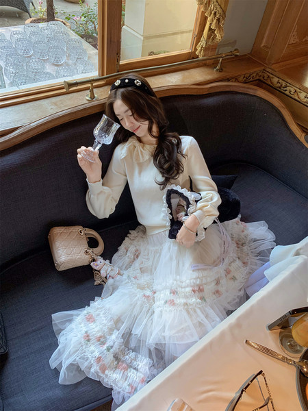 Woman wearing a cream sweater with a layered tulle floral skirt and black headband