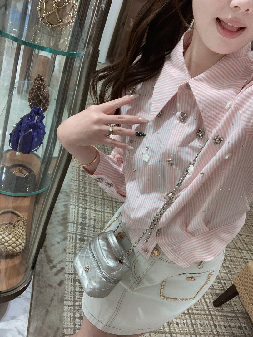 Woman wearing a pink striped embellished shirt with a light skirt and silver crossbody bag