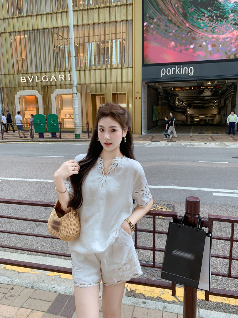Woman wearing a white embroidered matching top and shorts set with a woven handbag