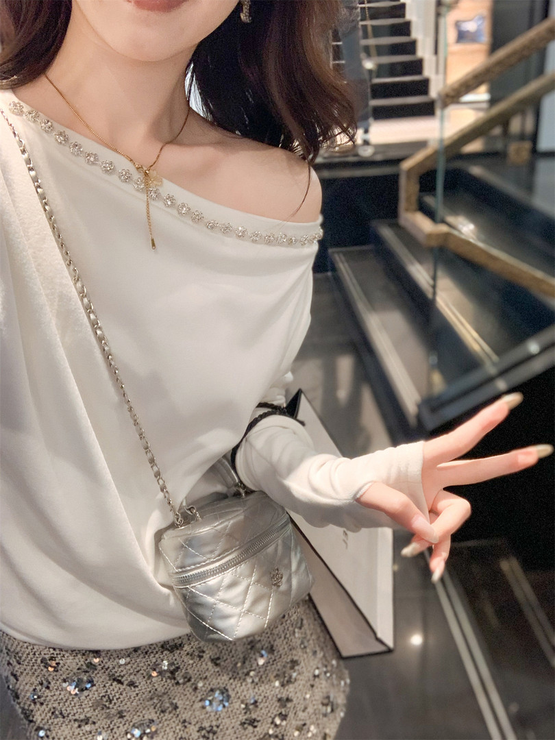 Woman wearing a white off-shoulder top with a small silver crossbody bag and sequined skirt