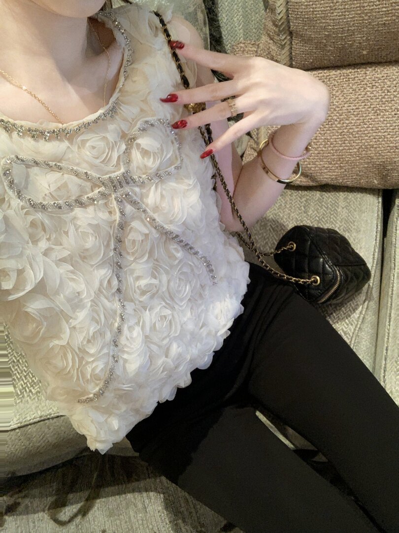 White floral embellished top worn with a black quilted mini bag