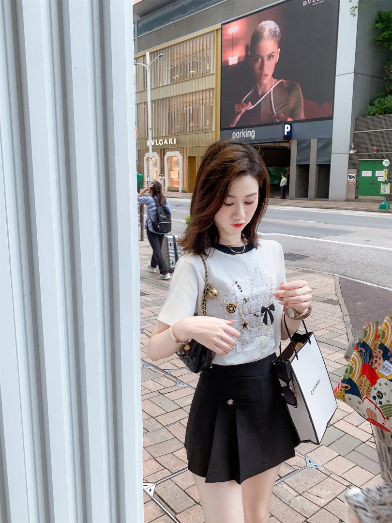 Woman wearing a white graphic T-shirt and black skirt in an outdoor street-style photo