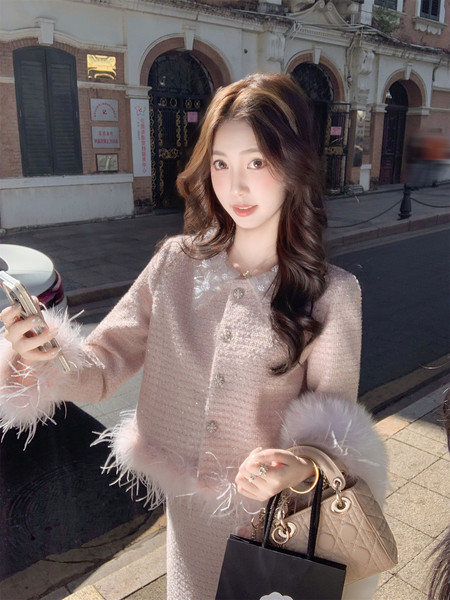 Woman wearing a pink fuzzy embellished cardigan or dress with feather trim