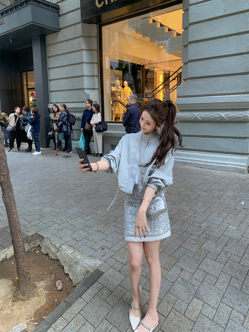 Woman wearing a silver sequin mini skirt with a light jacket and handbag outdoors