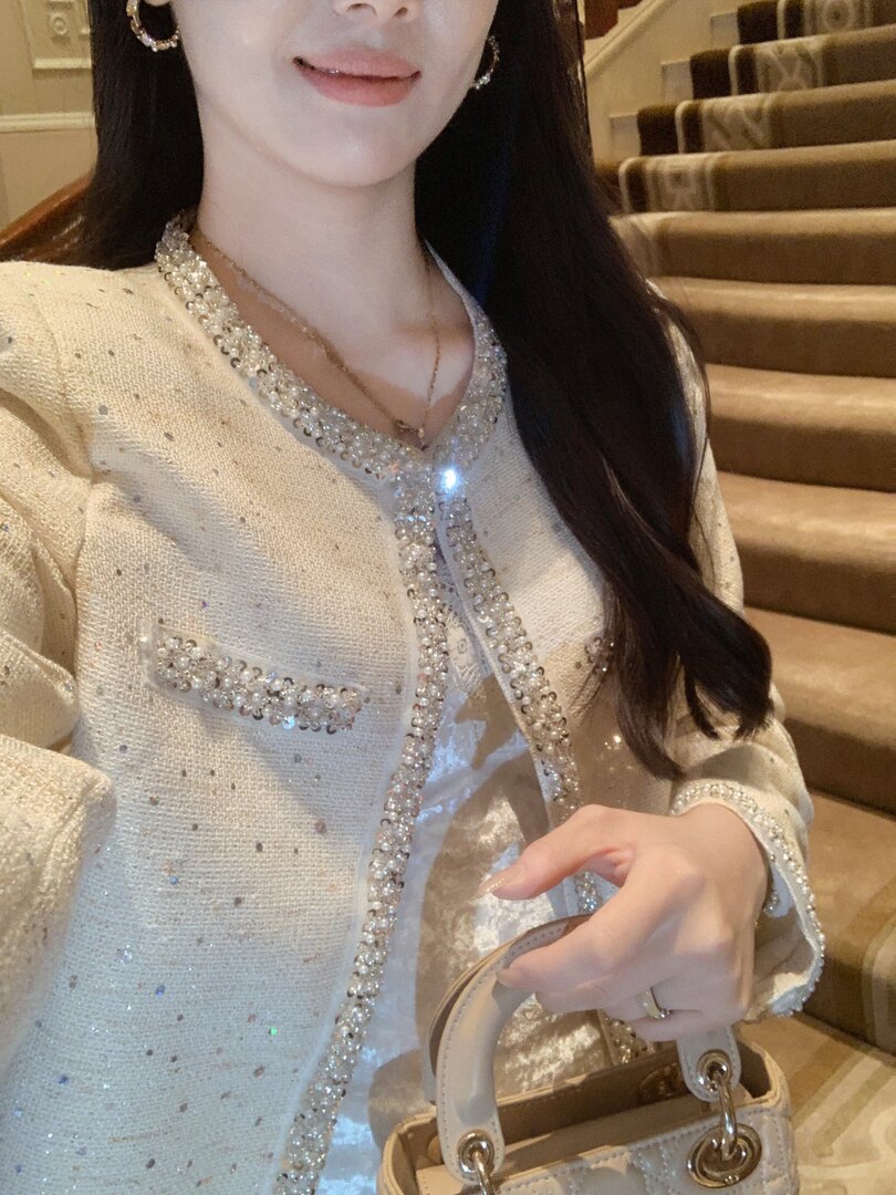 Woman wearing a sparkly embellished jacket and holding a matching handbag