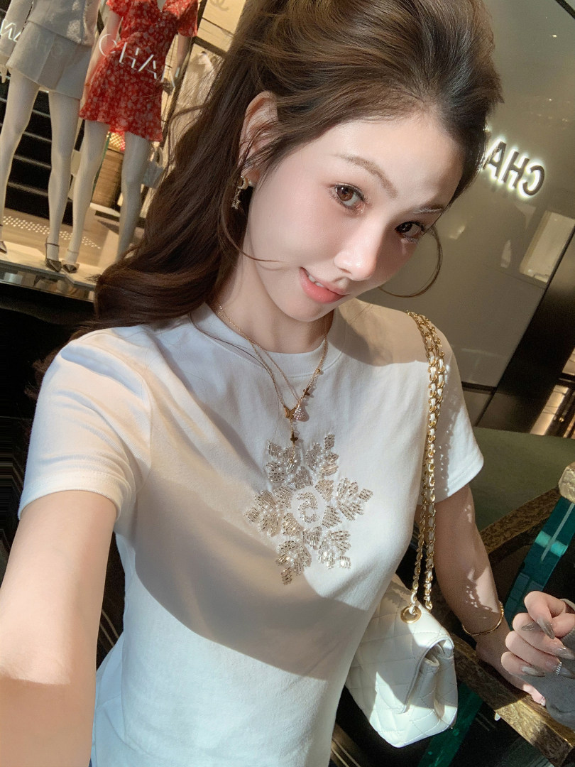 Woman wearing a white short-sleeve T-shirt with a beaded floral design