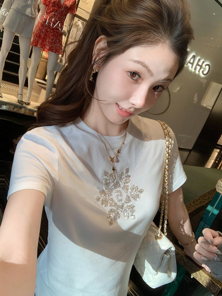 Woman wearing a white short-sleeve T-shirt with a beaded floral design