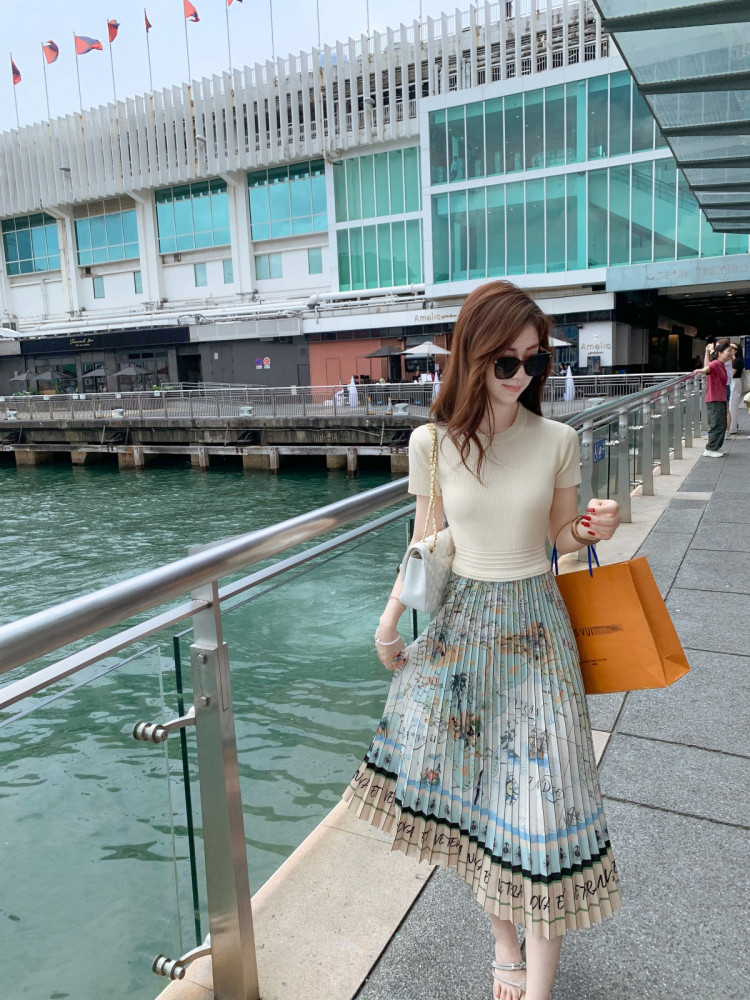 Woman wearing a cream top and pleated floral midi skirt outdoors