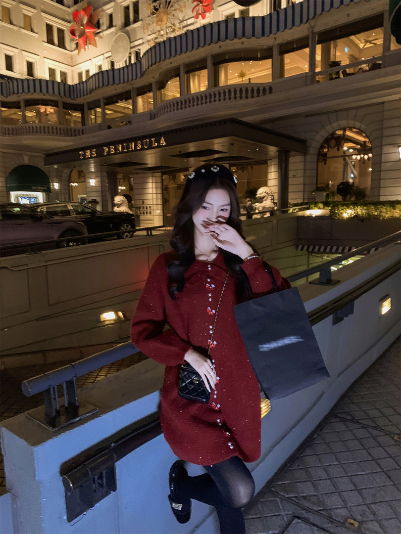 Woman wearing a red long-sleeve dress and holding a black quilted handbag at night