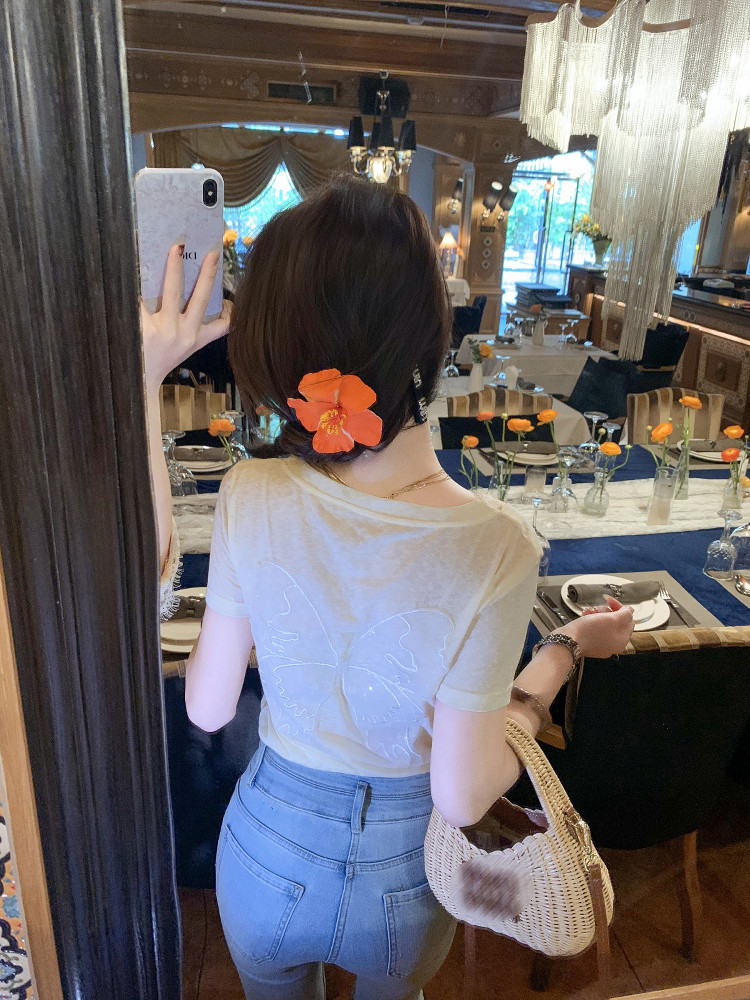 Woman wearing a white short-sleeve top with blue jeans and a woven handbag