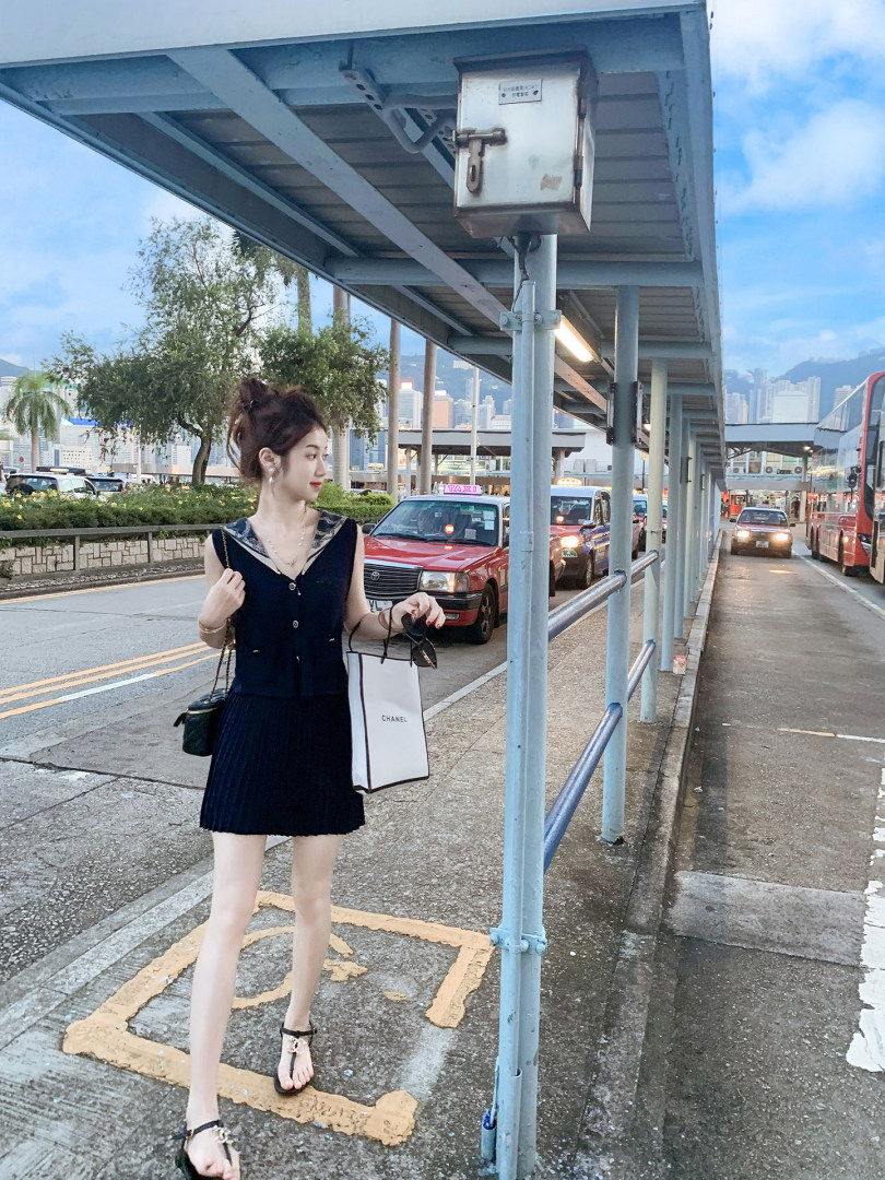 Woman wearing a black sleeveless pleated dress outdoors