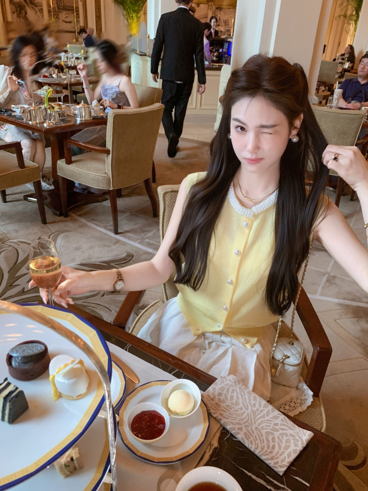 Woman wearing a yellow sleeveless button-front top at a restaurant