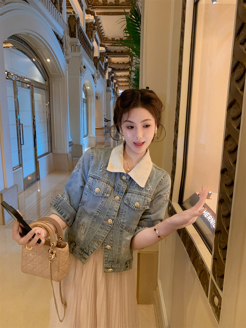 Woman wearing a light blue denim jacket over a dress in an indoor setting