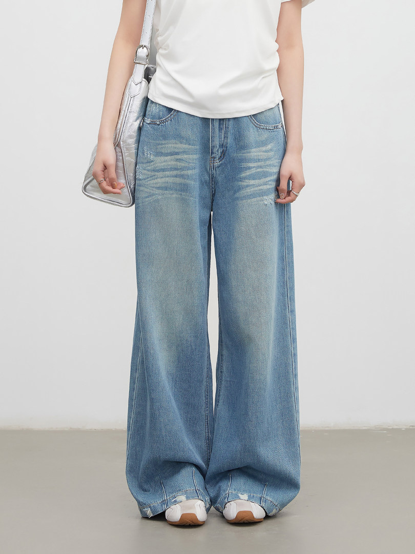 Model wearing light blue wide-leg jeans with a white top and silver shoulder bag