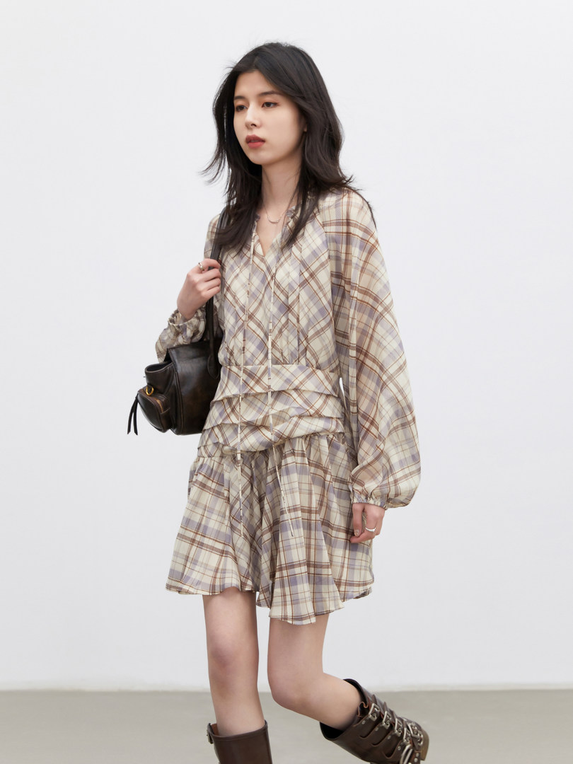Model wearing a beige plaid long-sleeve dress with matching skirt, black shoulder bag, and brown boots