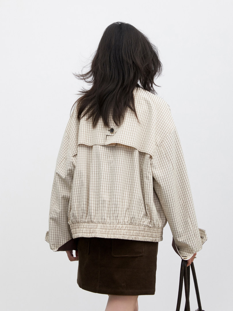 Woman wearing a beige checkered lightweight jacket viewed from the back