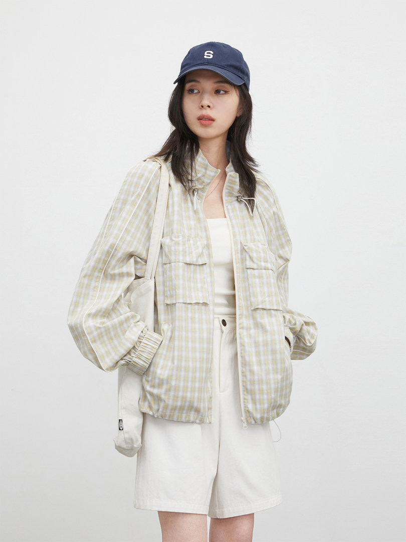 Model wearing a light plaid jacket, white shorts, and navy cap