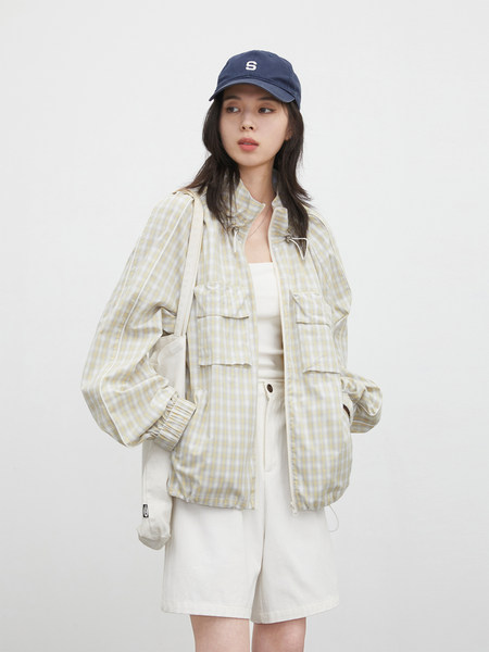 Model wearing a light plaid jacket, white shorts, and navy cap
