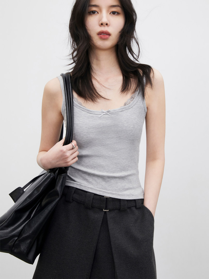 Model wearing a gray tank top with black wide-leg trousers and a black tote bag