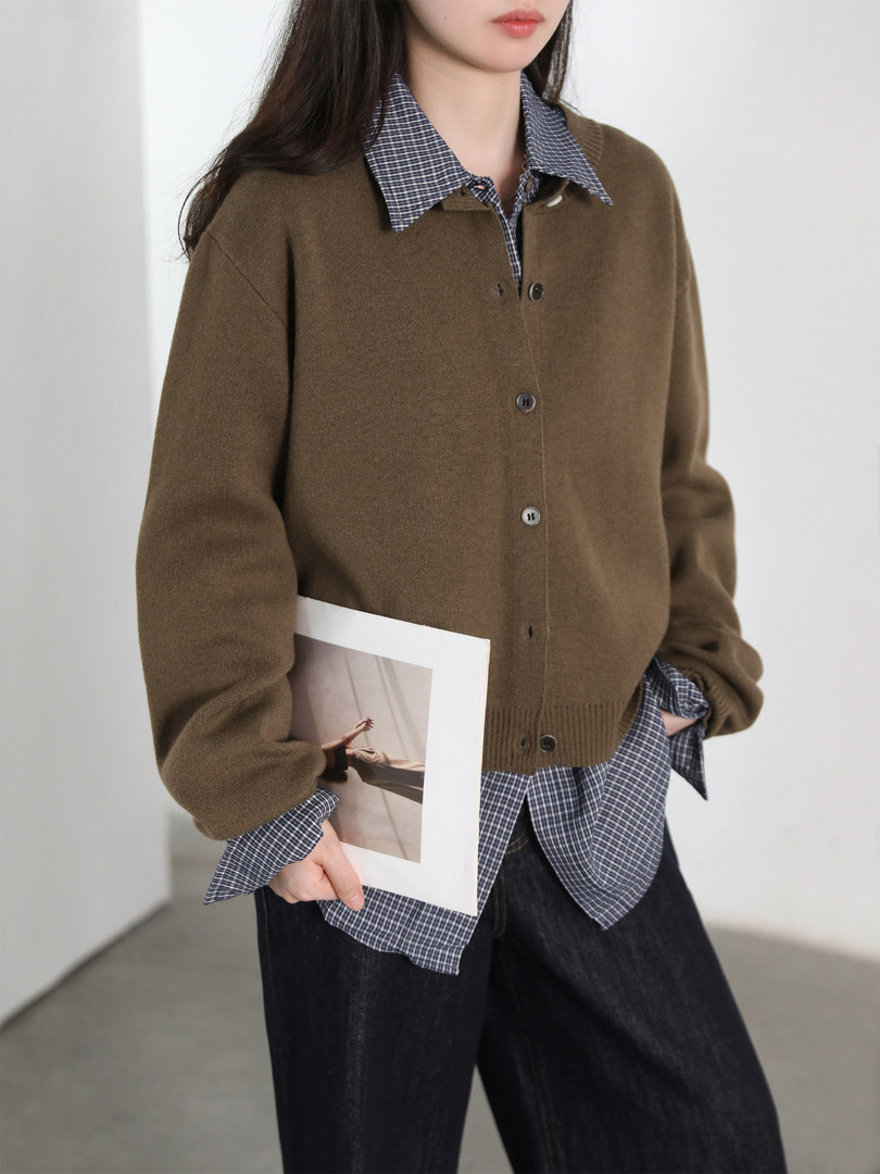 Brown knit button-front cardigan worn over a blue plaid shirt with dark pants