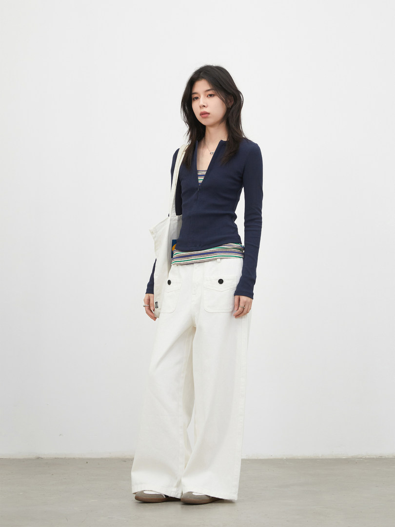 Model wearing a navy long-sleeve top with white wide-leg pants and a tote bag