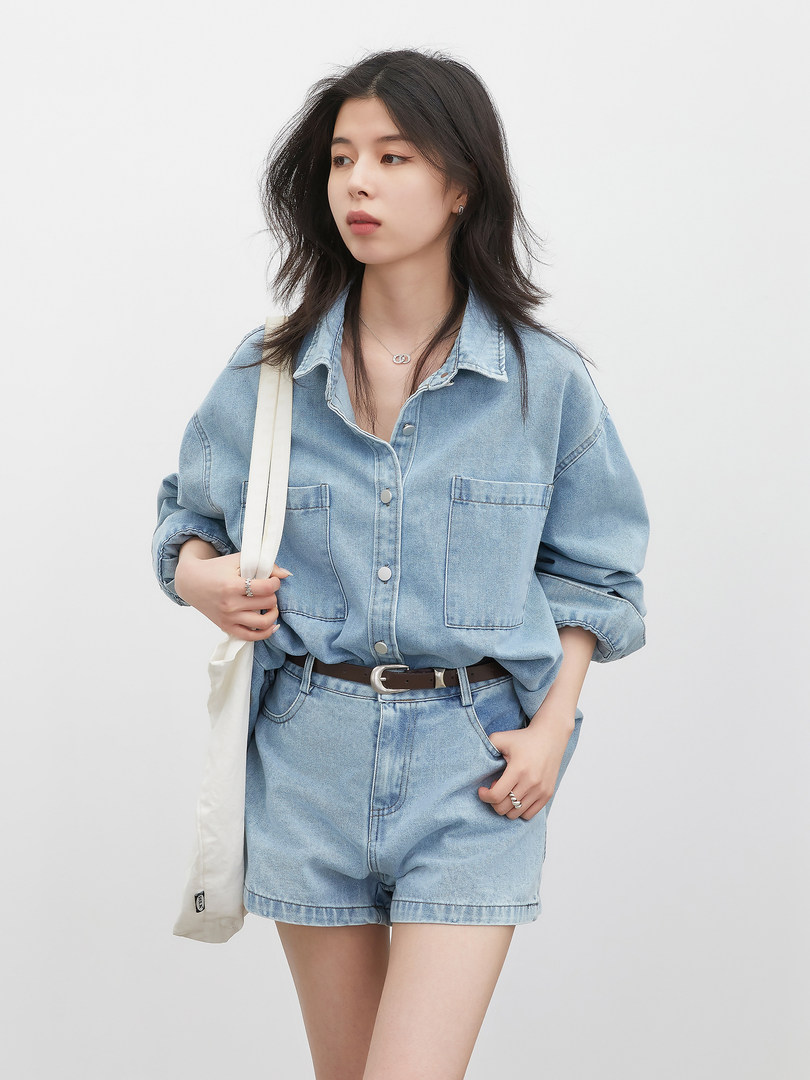 Model wearing a light blue denim shirt and matching shorts with a belt