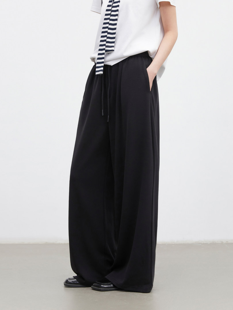 Model wearing black wide-leg pants with a white top and striped tie
