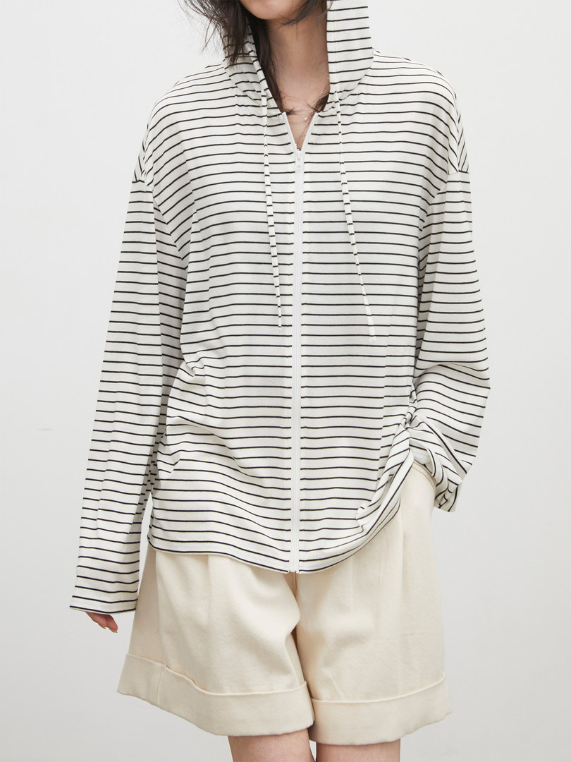 Model wearing a white striped zip-up hooded top with cream shorts
